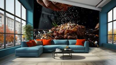 The concept of cooking meat. The chef cook salt on the cooked steak on a black background Wall mural