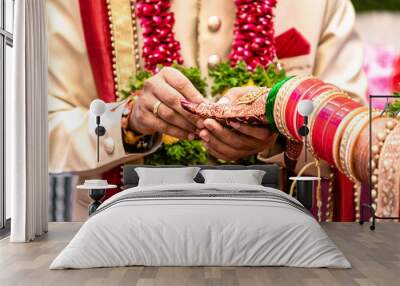 Engagement Ring ceremony- Indian Hindu male putting ring on bride's decorated finger. Couple is well attired as per traditional Indian Hindu wedding. Groom wearing Jodhpuri suit and floral garland. Wall mural