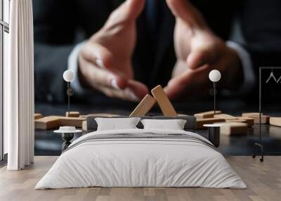 Businessman in suit with collapsed wooden blocks on desk, symbolizing failure or risk in corporate strategy. Wall mural