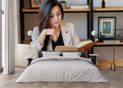 young Asian business woman working at workplace. beautiful Asian woman in casual suit working with reading book, prepare for meeting or interview in modern office. freelance, start up business in Asia Wall mural