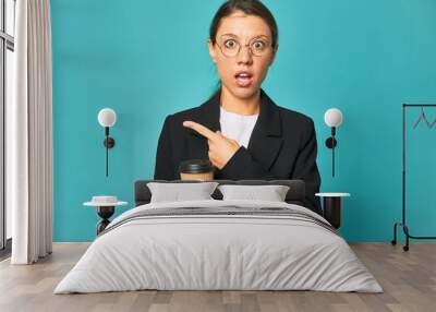 A young caucasian business woman holds a takeaway coffee pointing to the side Wall mural