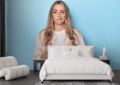 Blonde young caucasian woman in blue studio showing that she has no money. Wall mural