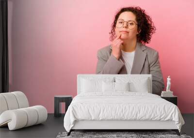 Business woman with Down syndrome isolated on pink background relaxed thinking about something looking at a copy space. Wall mural