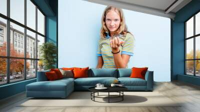 Caucasian teen girl isolated on blue background pointing with finger at you as if inviting come closer. Wall mural