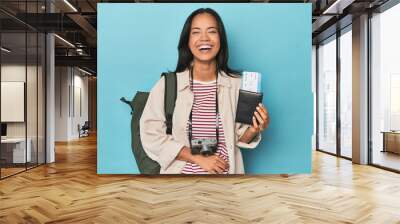 Filipina with camera, tickets, backpack on blue laughing and having fun. Wall mural