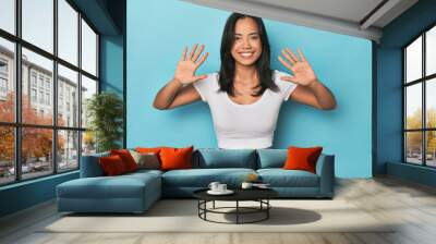 Filipina young woman on blue studio showing number ten with hands. Wall mural