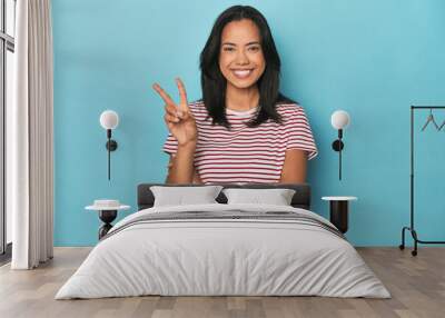 Filipina young woman on blue studio showing number two with fingers. Wall mural