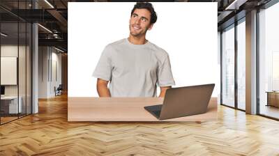 Hispanic young man working on laptop relaxed and happy laughing, neck stretched showing teeth. Wall mural