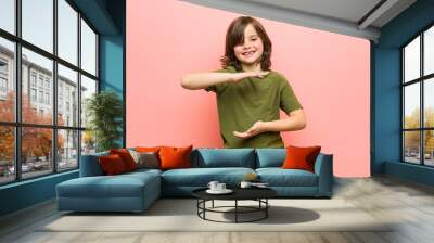 Little boy holding something with both hands, product presentation. Wall mural