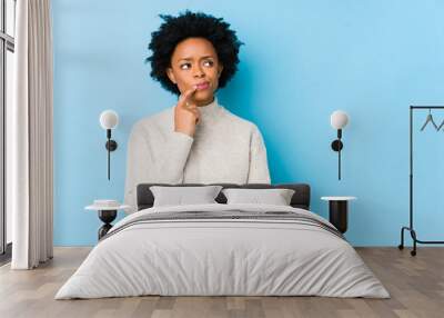 Middle aged african american woman against a blue background isolated looking sideways with doubtful and skeptical expression. Wall mural