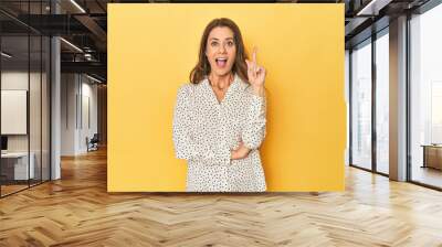 Middle-aged caucasian woman on yellow having an idea, inspiration concept. Wall mural