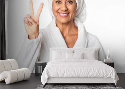 Middle-aged woman with towel post-shower in studio showing number two with fingers. Wall mural