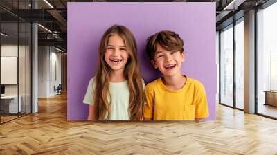 Portrait of two little children smiling and looking at camera against purple background Wall mural