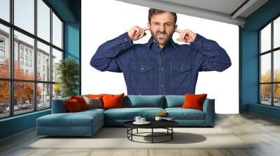 Studio portrait of young Hispanic male covering ears with fingers, stressed and desperate by a loudly ambient. Wall mural