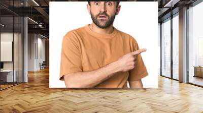 Studio portrait of young Hispanic male pointing to the side Wall mural