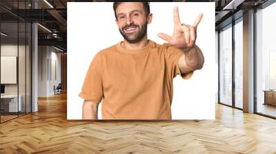 Studio portrait of young Hispanic male showing a horns gesture as a revolution concept. Wall mural