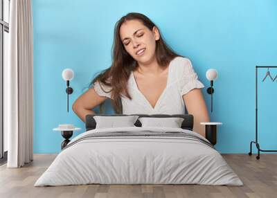 Stylish young woman in white blouse on a blue studio backdrop having a liver pain, stomach ache. Wall mural