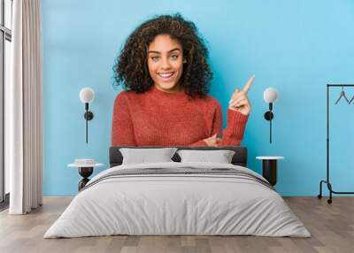 Young african american curly hair woman smiling cheerfully pointing with forefinger away. Wall mural