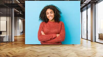 Young african american curly hair woman who feels confident, crossing arms with determination. Wall mural