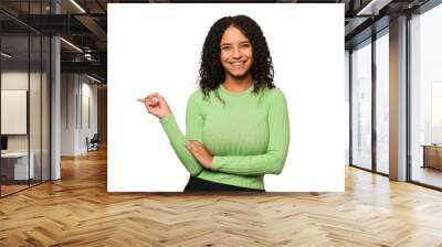 Young african american curly woman isolated smiling cheerfully pointing with forefinger away. Wall mural