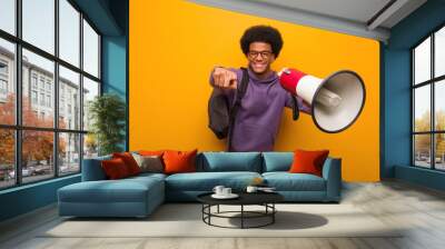 Young african american man holdinga a megaphone cheerful and smiling pointing to front Wall mural