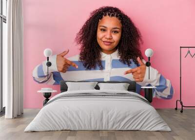 Young african american woman isolated on pink background person pointing by hand to a shirt copy space, proud and confident Wall mural