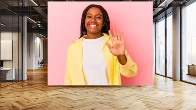 Young african american woman isolated on pink background  smiling cheerful showing number five with fingers. Wall mural