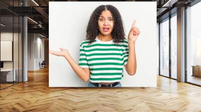 Young african american woman isolated on white background holding and showing a product on hand. Wall mural