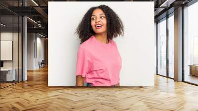 Young african american woman isolated on white background looks aside smiling, cheerful and pleasant. Wall mural