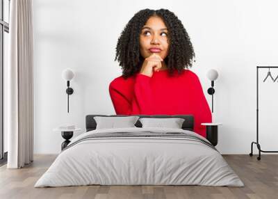 Young african american woman isolated relaxed thinking about something looking at a copy space. Wall mural