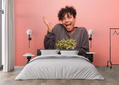 Young african american woman with a birthmark holding a plant pot Wall mural