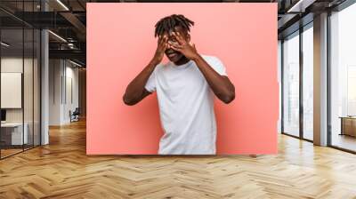 Young african black man blink through fingers frightened and nervous. Wall mural