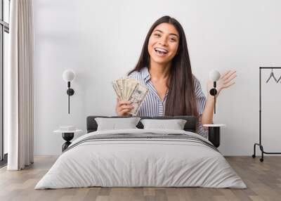 Young arab woman holding dollars celebrating a victory or success Wall mural