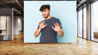 Young arabian man isolated on a blue background rejecting someone showing a gesture of disgust. Wall mural