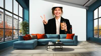 Young architect English woman with helmet and holding blueprints isolated on blue background showing number two with fingers. Wall mural