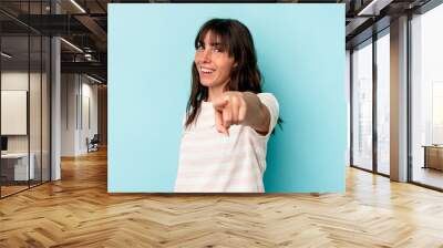 Young Argentinian woman isolated on blue background cheerful smiles pointing to front. Wall mural