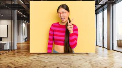 Young Asian woman isolated on yellow background showing number two with fingers. Wall mural