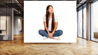 Young asian woman sitting on the floor cutout isolated relaxed and happy laughing, neck stretched showing teeth. Wall mural