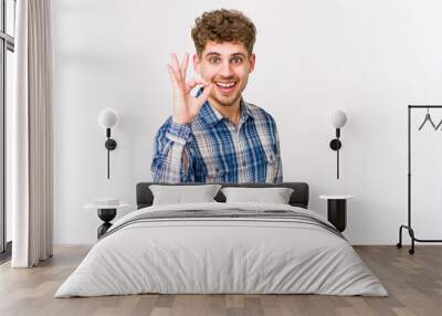 Young blond curly hair caucasian man isolated cheerful and confident showing ok gesture. Wall mural