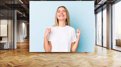 Young blonde caucasian woman isolated celebrating a victory, passion and enthusiasm, happy expression. Wall mural