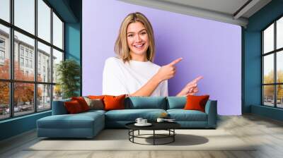 Young blonde caucasian woman isolated excited pointing with forefingers away. Wall mural