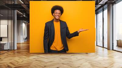 Young business african american man over an orange wall holding something with hand Wall mural