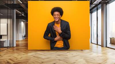 Young business african american man over an orange wall laughing and having fun Wall mural