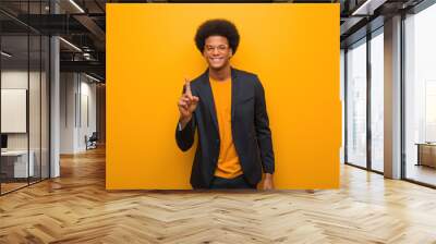 young business african american man over an orange wall showing number one Wall mural