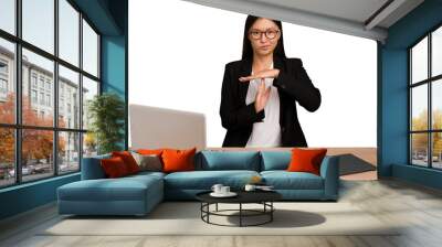 Young business asian woman sitting on a table isolated showing a timeout gesture. Wall mural