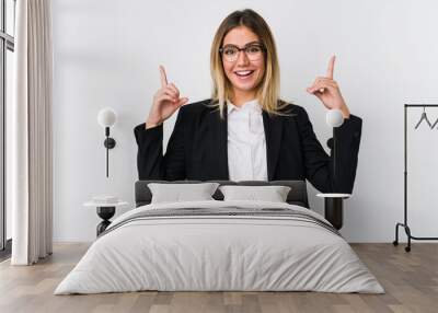 Young business caucasian woman indicates with both fore fingers up showing a blank space. Wall mural