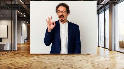 Young business man isolated on white background winks an eye and holds an okay gesture with hand. Wall mural