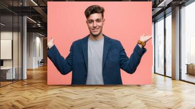 Young business natural man makes scale with arms, feels happy and confident. Wall mural