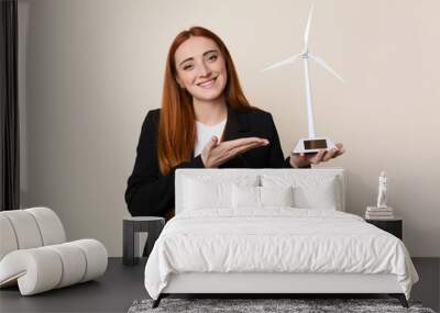 Young business woman holding a windmill, clean energy concept Wall mural