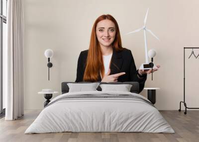 Young business woman holding a windmill, clean energy concept Wall mural